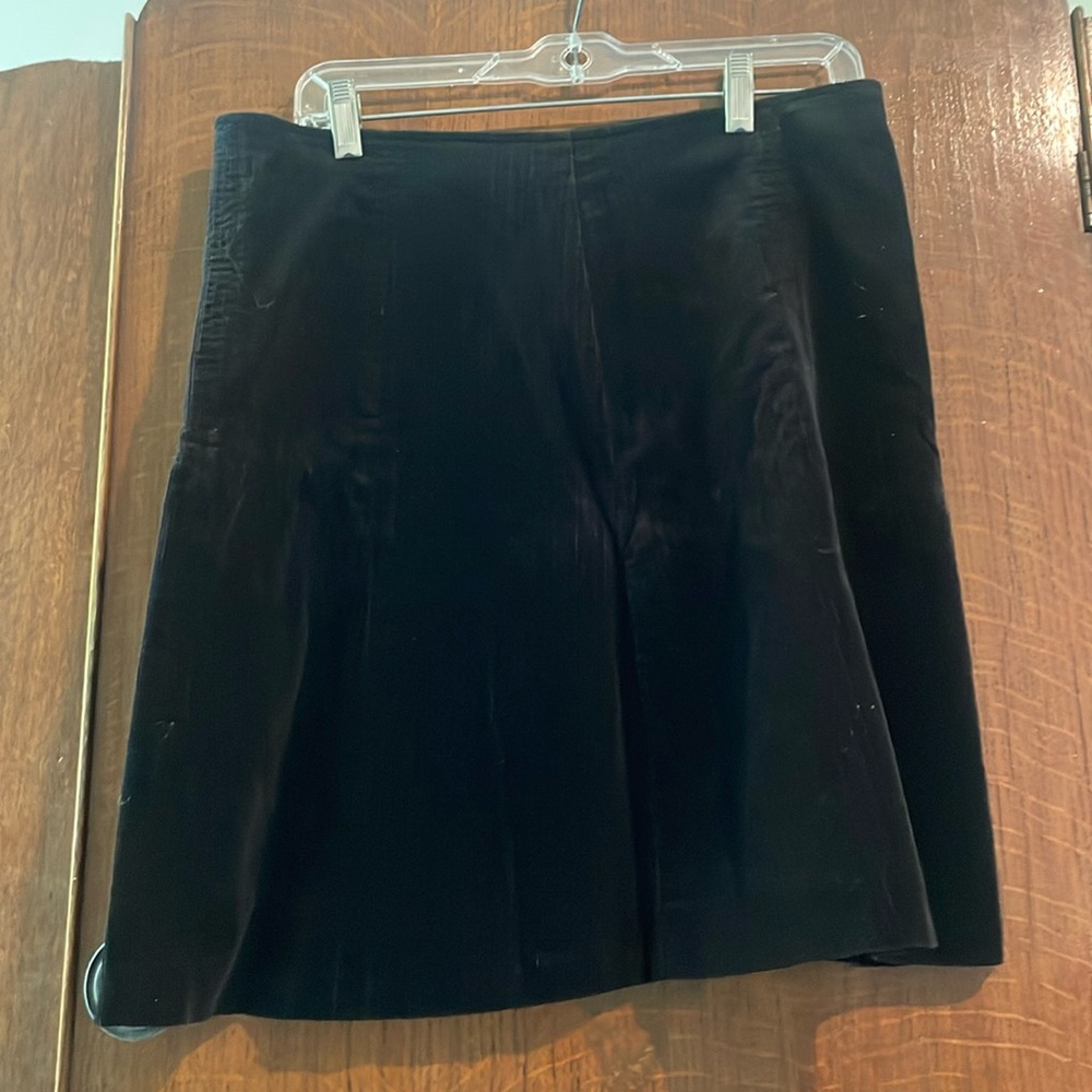 Short black corduroy skirt. Zips on the side. Slight A-line.
